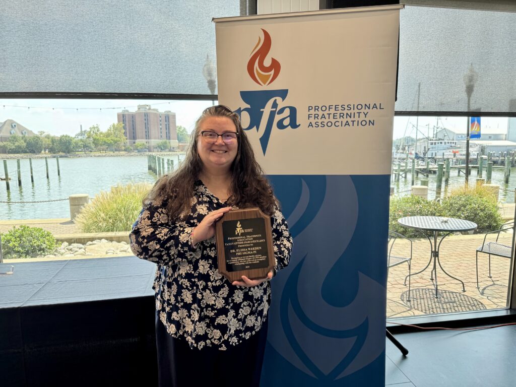 Elissa Weeden holds the award plaque for Faculty Advisor Award of Excellence