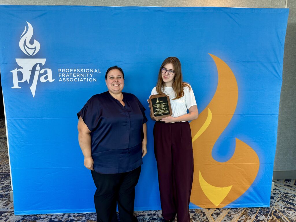 Lauren Zeigler holds the award plaque for Outstanding Volunteer Service Award, standing next to Sarah Smith.